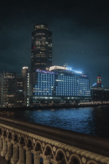 A towering, illuminated building on the riverbank at night against a dark sky, London, England, Great Britain