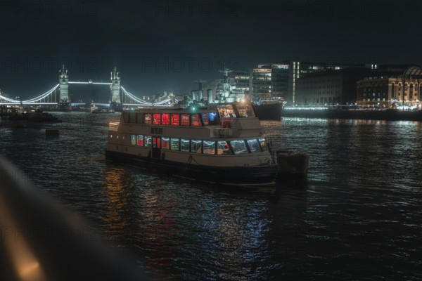 Illuminated boat on the Thames at night with Tower Bridge in the background, London, England, Great Britain