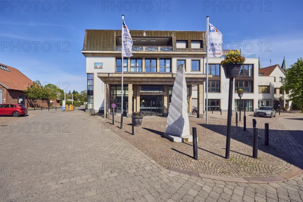Volksbank Dammer Berge eG Hauptstelle Damme, general architecture, commercial building, modern building, advertising flags on flagpoles, barrier bollards, road made of paving stones and concrete paving stones, trees, blue sky, cirrus clouds, Mühlenstraße, dam, district of Vechta, Lower Saxony, Germany