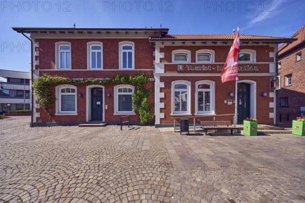 Tourist information, advertising flags on flagpoles, brick buildings, houses, bench, walkway made of natural stone slabs and paving stones, blue sky, cirrus clouds, Mühlenstraße, Damme, Vechta district, Lower Saxony, Germany