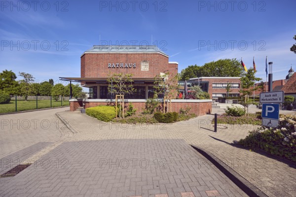Town hall, brick building, modern architecture, flat roof, parking space for the disabled, barrier bollard, street made of concrete paving stones, flag poles, flower bed, hedge, trees, lawn, blue sky, cirrus clouds, Mühlenstraße, Damme, district of Vechta, Lower Saxony, Germany