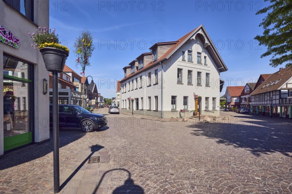 Social department store Kleines Kaufhaus Damme, general architecture, commercial buildings, houses, façade with windows, dormers, street made of paving stones, cars, maypole, flower pots, blue sky, cirrus clouds, intersection of Große Straße, Friedhofstraße and Gartenstraße, Damme, district of Vechta, Lower Saxony, Germany