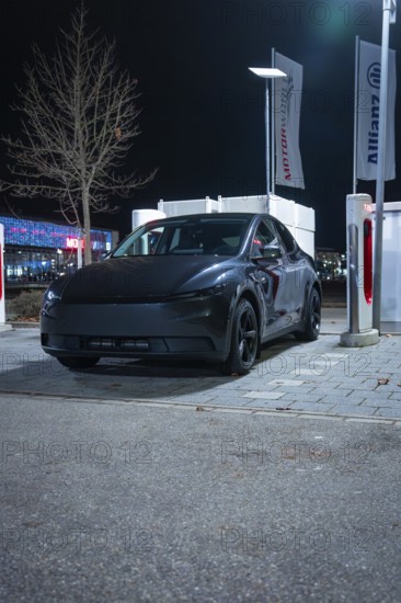 A black Tesla at night in a parking lot at a charging station, New Model Y Standard, Tesla Supercharger, Böblingen, Germany