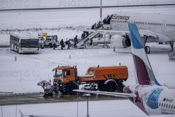 The onset of winter in North Rhine-Westphalia, flight operations are maintained at Düsseldorf airport with great effort, taxiways, passenger boarding, outdoor position, Eurowings, runway are freed from snow and ice with many clearing vehicles, airplanes are de-iced in front of takeoff, North Rhine-Westphalia, Germany