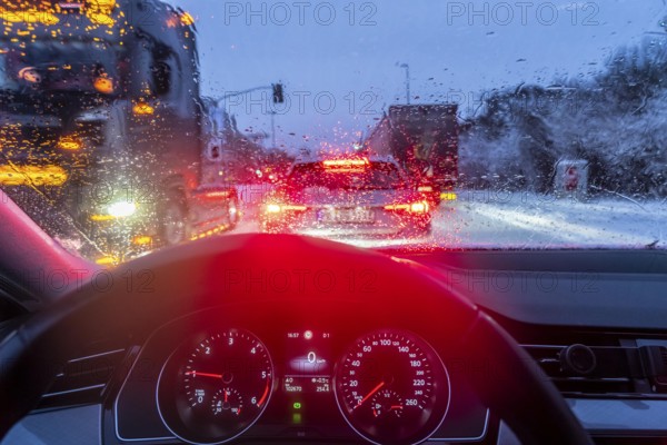 Driving in winter, in snow, rain, rear lights, brake lights, speedometer, cockpit
