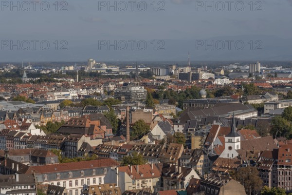 The stone balcony offers a view of the city of Strasbourg. Houses and buildings can be seen under a cloudy sky. Architectural details surround the balcony. Bas Rhin, Alsace, France