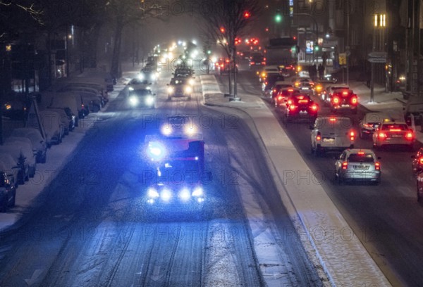 Ambulance, RTW, the Essen professional fire brigade during an emergency trip with flashing lights, winter weather, blowing snow, inner-city road traffic, Alfredstraße, B224, in Essen, North Rhine-Westphalia, Germany