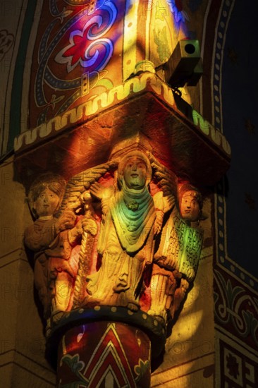 Issoire. Pillar (The Annunciation made to Mary) . The figures are illuminated by colorful light shining through a stained glass window inside Saint Austremoine Abbey, Puy de Dome, Auvergne Rhone Alpes, France