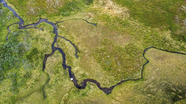Aerial view of green fells and moorland crossed by streams, river traversing lush, green landscape in a twisting shape, Berlevåg, Finnmark, Norway