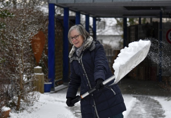 Elderly woman sweeping week with snow shovel, snow shovel, snow remover, shovel, clear, shovel snow, carport, sidewalk, snowfall, snow, winter, Stuttgart, Baden-Württemberg, Germany