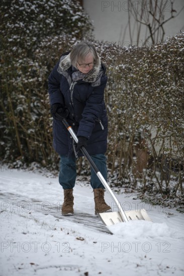 Elderly woman sweeping week with snow shovel, snow shovel, snow remover, shovel, clear, shovel snow, sidewalk, snowfall, snow, winter, Stuttgart, Baden-Württemberg, Germany