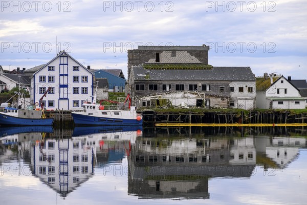 Fishing boats Fishing vessels are moored in Berlevag harbour in the north of the Varanger Peninsula with white and dilapidated buildings in the background, Berlevåg, Finnmark, Norway