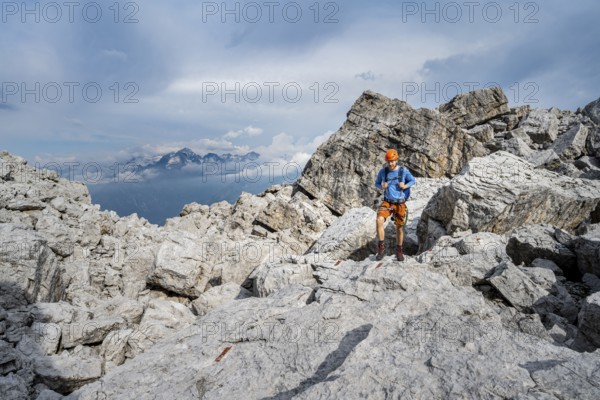 Mountaineers between large boulders, rocky mountain landscape, Via Ferrata SOSAT via Ferrata, in the background mountain peaks of the Adamello GroupBrenta Mountains, Trentino, Italy