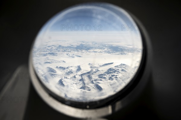 View from an airplane window of snowy arctic mountain landscape with glaciers, aerial view, Greenland, Arctic