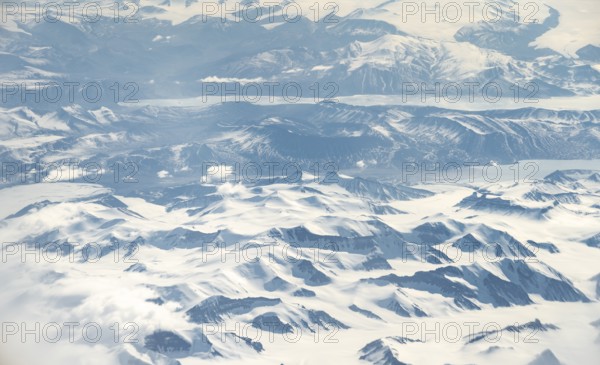 Icy, snowy arctic mountain landscape with glaciers and fjords, aerial view, Greenland, Arctic