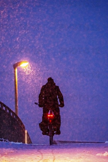 Winter weather, blowing snow, person with e-bike, bicycle on snowy bridge, footpath bridge, steep uphill, North Rhine-Westphalia, Germany