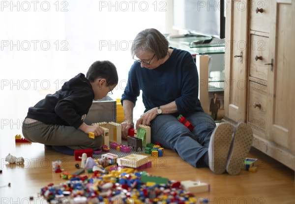 Elderly woman, grandma, boy, 6 years, grandson, glasses, multi-ethnic, playing together with Lego, concentrating, constructing, building, Stuttgart, Baden-Württemberg, Germany