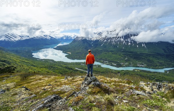 Climber enjoying the view, Slaughter Ridge Trail, view of snowy mountains and turquoise blue Kenai Lake, Cooper Landing, Kenai Peninsula, Alaska, USA