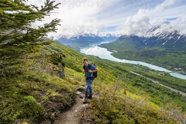 Climbers on a hiking trail, Slaughter Ridge Trail, view of snowy mountains and turquoise lake Kenai Lake, Cooper Landing, Kenai Peninsula, Alaska, USA