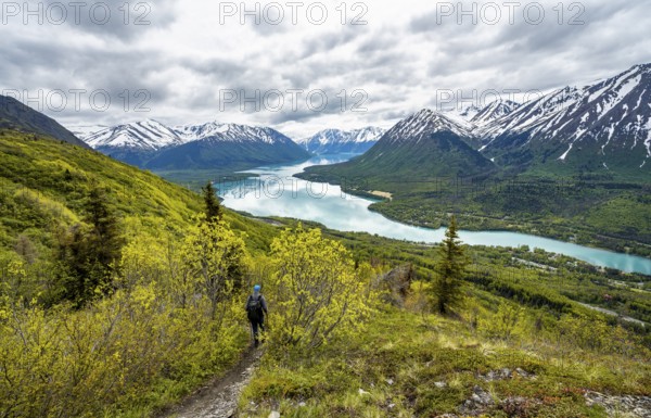 Climbers on a hiking trail, Slaughter Ridge Trail, view of snowy mountains in spring and turquoise blue Kenai Lake Lake, Cooper Landing, Kenai Peninsula, Alaska, USA