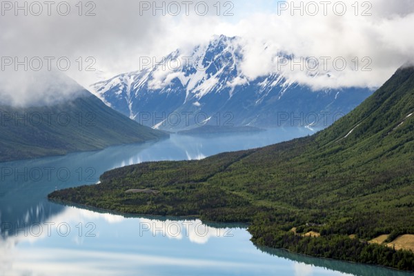 View of snowy mountains in spring and turquoise Kenai Lake with reflection, Slaughter Ridge Trail, Cooper Landing, Kenai Peninsula, Alaska, USA