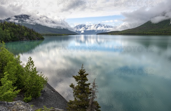 Snowy mountains in spring are reflected in turquoise blue Kenai Lake, Cooper Landing, Kenai Peninsula, Alaska, USA