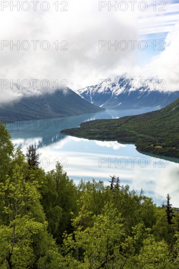 View of snowy mountains in spring and turquoise Kenai Lake with reflection, Slaughter Ridge Trail, Cooper Landing, Kenai Peninsula, Alaska, USA