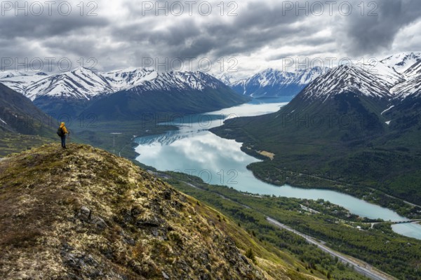 Climbers on a hiking trail on Slaughter Ridge, views of snowy mountains in spring and turquoise Lake Kenai Lake, Cooper Landing, Kenai Peninsula, Alaska, USA