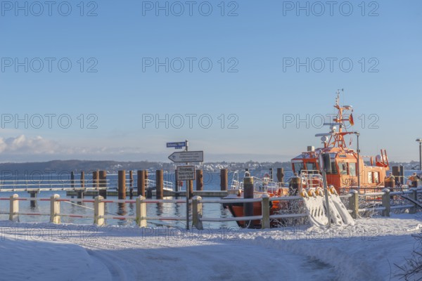 Kiel-Holtenau pilot station in front of the Kiel Canal, pilot boat, channel guidance, shipping, safety, dolphins, pier, Kiel Fjord, Baltic Sea, on the horizon east shore with Heikendorf, calm sea, winter, snowfall, sunshine, blue sky, Kiel, Germany