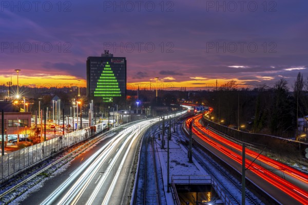 Autobahn A40, Ruhrschnellweg, between Essen and Mülheim an der Ruhr, evening traffic in winter, former, now vacant Stinnes high-rise building, at the Rhine-Ruhr Center, showing a green Christmas tree from illuminated windows at Christmas time, North Rhine-Westphalia, Germany