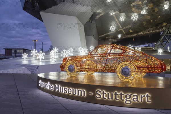 Highlights on Porscheplatz in Zuffenhausen. In front of the Porsche Museum and the car manufacturer's headquarters, a 911 sports car shines in Christmassy splendor. Stuttgart, Baden-Württemberg, Germany