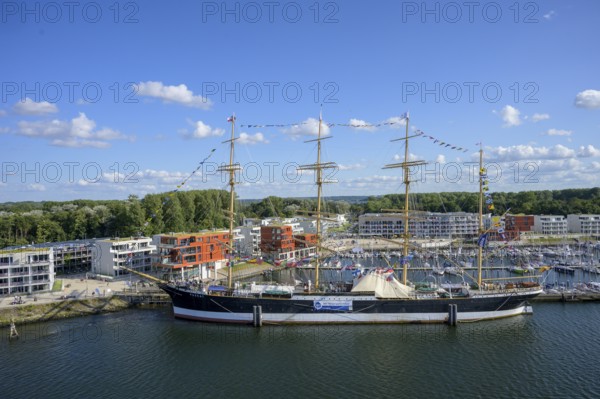 Harbour view with the legendary four-masted PASSAT barque and many boats in front of modern buildings under blue skies, Travemünde, Lübeck, Schleswig-Holstein, Germany