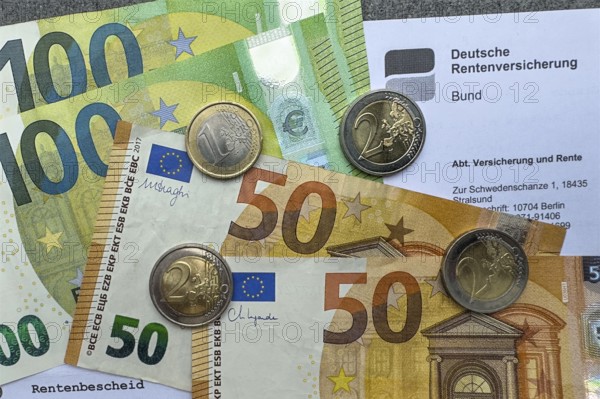 Symbolic photo document pension certificate from Deutsche Rentenversicherung on it cash banknotes 50 100 euro banknotes and euro coins coins, Germany