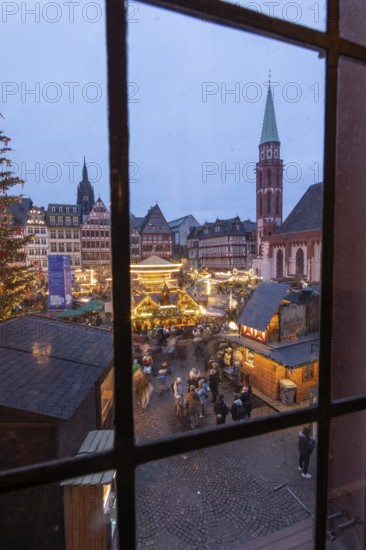 December 22, 2025, View from a window inside the Roemer looking down at the Frankfurt Christmas Market on Roemerberg at twilight. Festive lights and stalls fill the historic square below, Frankfurt, Hesse, Germany