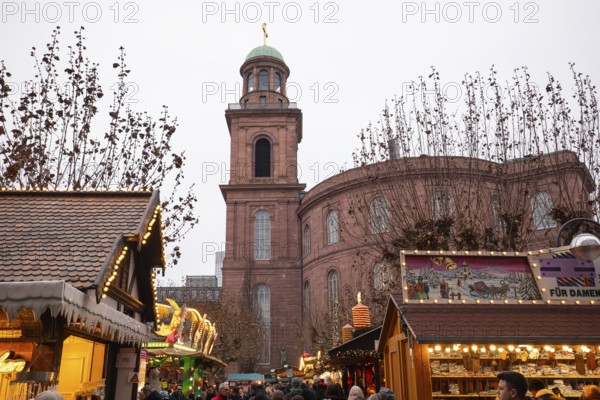 December 22, 2025, people strolling past festive wooden stalls at the Christmas market near St. Paul's Church, Frankfurt, Hesse, Germany