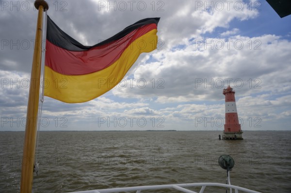 German flag and Angaster lighthouse in Jade Bay taken from an excursion ship, Jade Bay, Lower Saxony, Germany