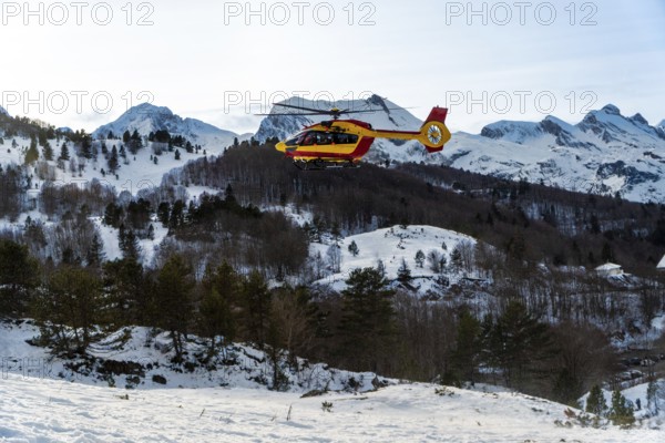 Rescue helicopter performing a search and rescue operation, transporting personnel and equipment across a snowy mountain range, demonstrating emergency medical services and alpine safety