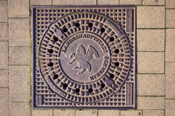 Manhole cover, city coat of arms, concrete paving stone walkway, Schwerin, state capital, district-free city, Mecklenburg-Western Pomerania, Germany