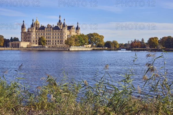 Castle, lake Burgsee, reed (Phragmites australis), trees, bushes, water surface with small waves, blue sky, cumulus clouds, cirrostratus clouds, Schwerin, state capital, independent city, Mecklenburg-Vorpommern, Germany