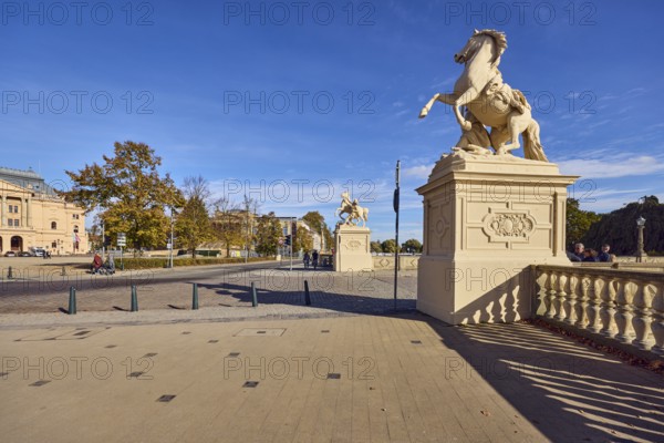Castle bridge, entrance portal, horse sculpture, car bridge and footbridge, sidewalk, sandstone railing, shade of railing, lantern, general architecture, trees with autumn leaves, pedestrians as accessories, blue sky, cumulus clouds, Lennéstraße, Werderstraße and Schlossstraße intersection, Schwerin, state capital, district-free city, Mecklenburg-Western Pomerania, Germany