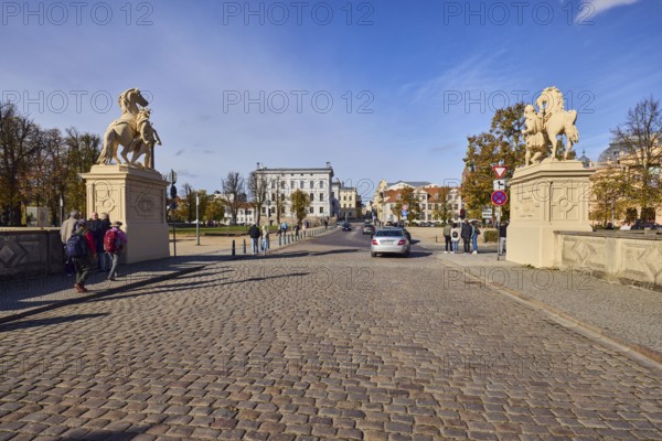 Entrance portal, horse sculpture, car bridge and footbridge, cobblestones, barrier bollard, sidewalk, historic building, general architecture, car, pedestrian as accessories, blue sky, cumulus clouds, cirrostratus clouds, castle bridge, intersection of Lennéstraße, Werderstraße and Schlossstraße, Schwerin, state capital, district-free city, Mecklenburg-Western Pomerania, Germany