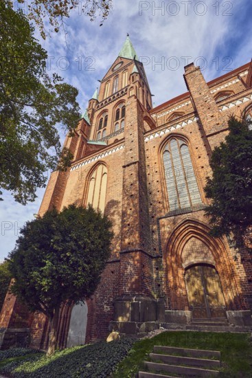 Schwerin Cathedral, St. Mary's Cathedral in Schwerin - Ev. -Luth. Schwerin cathedral, tower, brick Gothic, neo-Gothic style, entrance door, stained-glass window, trees, branches, blue sky, cumulus clouds, street Am Dom, Schwerin, state capital, district-free city, Mecklenburg-Western Pomerania, Germany