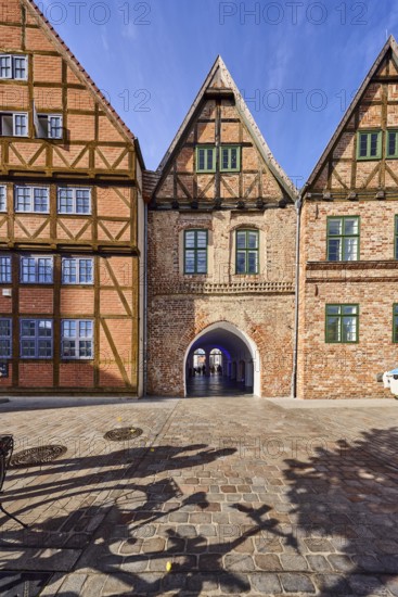 Row of houses, old town, half-timbered building, brick building material, residential building, passage arch, cobblestone walkway, shadow of a bicycle and people, blue sky, cirrostratus clouds, butcher market, Schwerin, state capital, district-free city, Mecklenburg-Western Pomerania, Germany