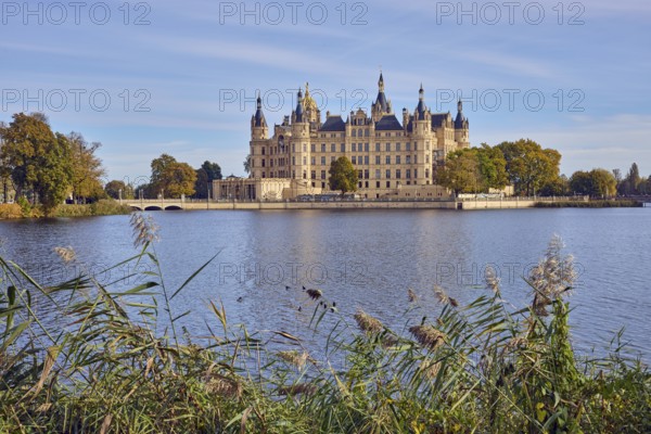 Castle, lake Burgsee, reed (Phragmites australis), trees, bushes, car bridge and pedestrian bridge, water surface with small waves, blue sky, cumulus clouds, cirrostratus clouds, Schwerin, state capital, independent city, Mecklenburg-Vorpommern, Germany