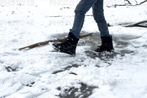 Berlin, Germany - December 31, 2025: A boy tests the frozen ice cream on the tailored Krummen Lanke on the last day in 2025 as snow falls in Berlin-Zehlendorf