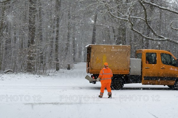 Berlin, Germany - 31 December 2025: A BSR (Berliner Stadtreinigung) employee spreads road salt on the street as snow falls in Berlin-Zehlendorf on the last day of 2025