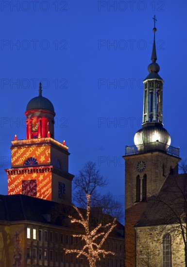 The Christmassy illuminated town hall tower and the illuminated church tower of St. John's Church in Witten, Ruhr area, North Rhine-Westphalia, Germany