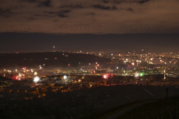 View from Kapellberg near Fellbach across the Neckar Valley to Stuttgart on New Year's Eve from 2025 to 2026. The television tower on the horizon as firecrackers and rockets light up the night sky at the turn of the year and greet the new year