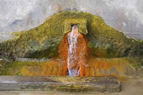 Rust-brown water flows from a spring in a concrete wall surrounded by eroded mineral deposits, mineral spring, Bolnissi, Katharinenfeld, Lower Kartli region, Kwemo Kartli, Georgia