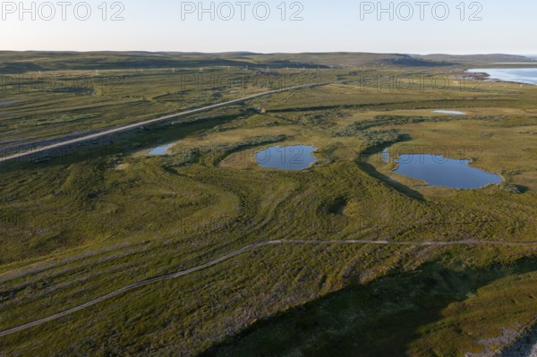 Coastal landscape on Varangerfjord with blue sky, still sea, moors and pebble beach aerial view, Barents Sea, Finnmark, Norway